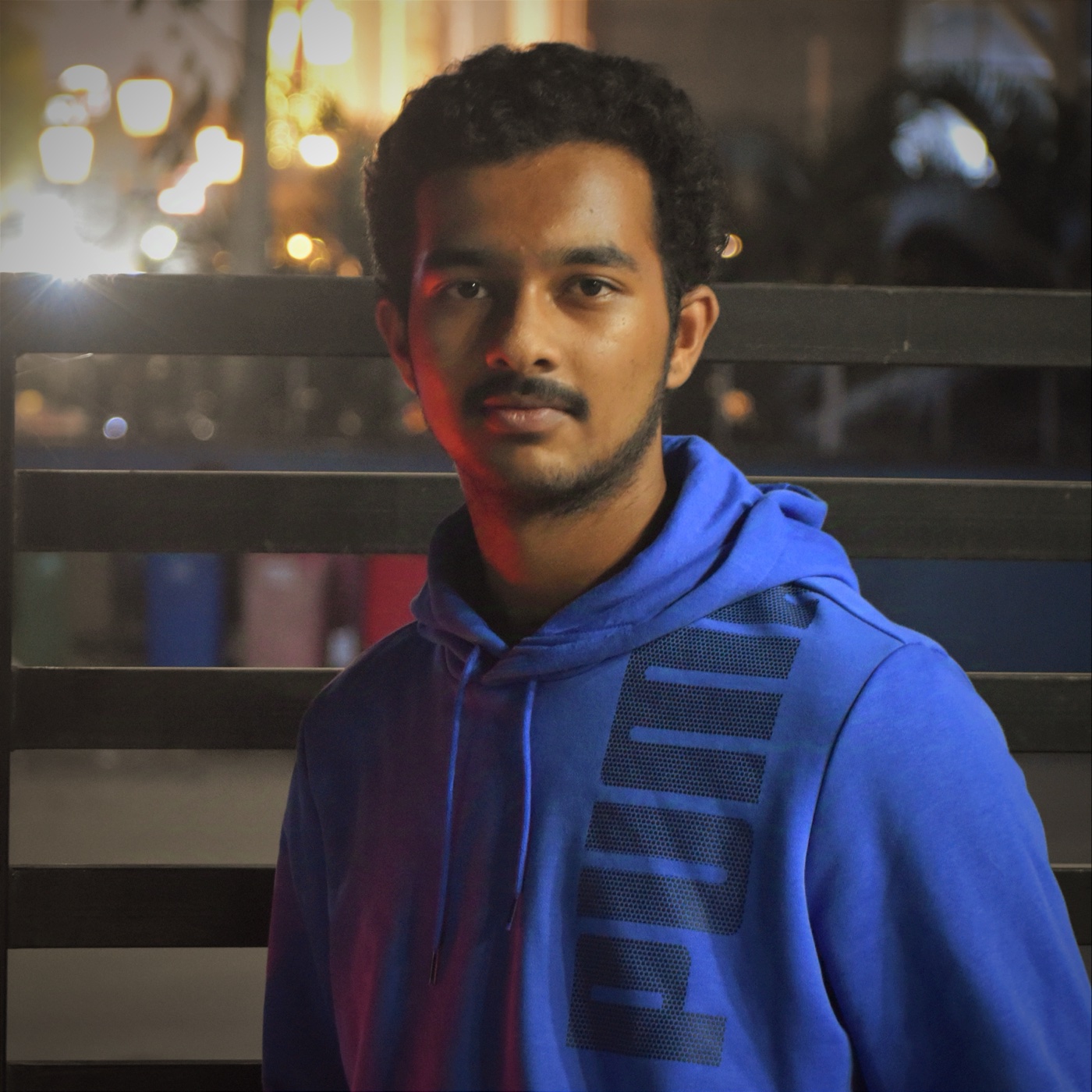 Ganesh wearing a blue hoodie, photographed outdoors at night